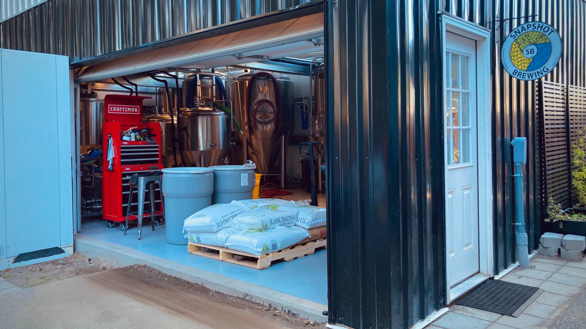 Snapshot Brewing's brewhouse with the bay door open onto the stainless tanks